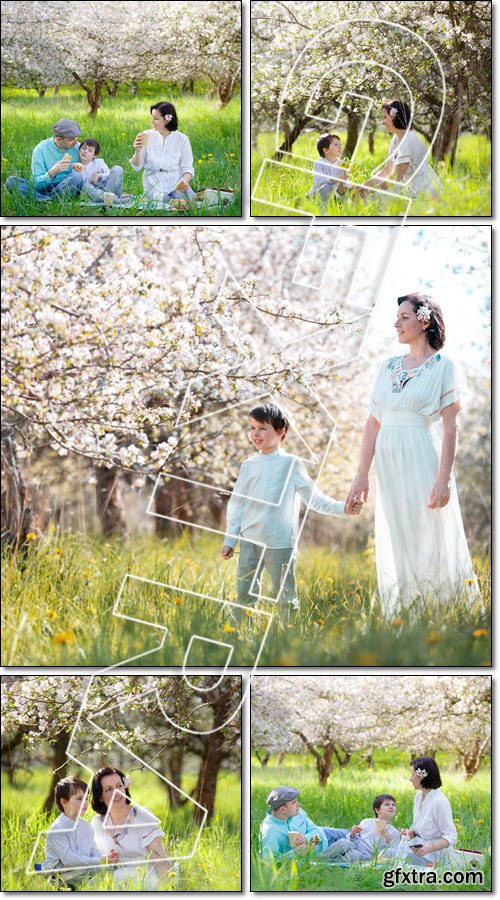 Young family picnicking in blooming apple garden - Stock photo