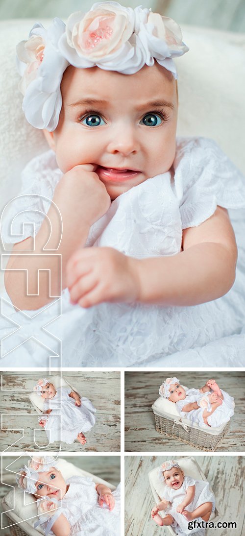 Stock Photos - Little girl in a dress lying in a basket on the wooden floor. Beautiful baby with big eyes