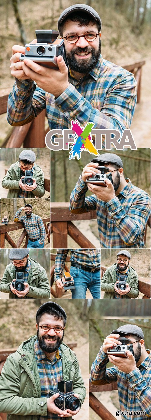 Young man with beard photographs movie in wood