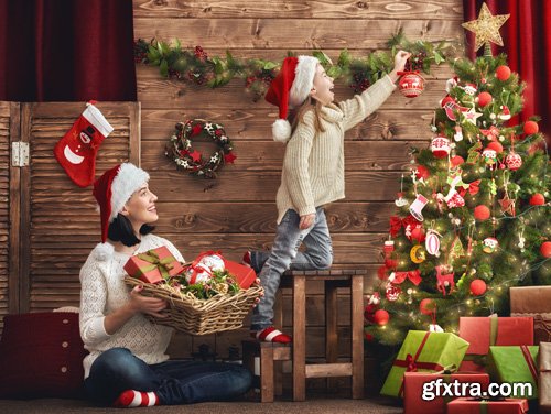 Happy family at Christmas, mother and daughter decorate the Christmas tree and exchange gifts