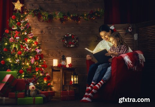 Happy family at Christmas, mother and daughter decorate the Christmas tree and exchange gifts