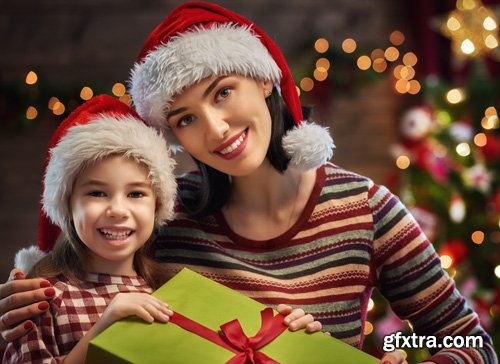 Happy family at Christmas, mother and daughter decorate the Christmas tree and exchange gifts