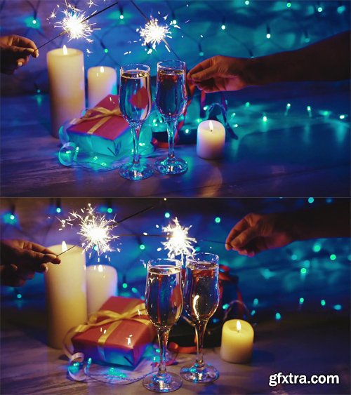 Hands with sparklers on the background of the Christmas decor, candles, gifts and glasses of champagne