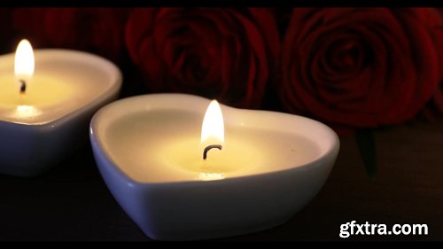 Close up of Heart Shaped Candles Burning in Front of Red Roses