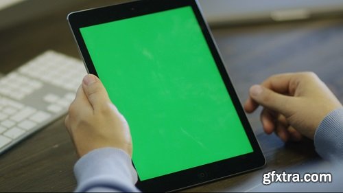 Designer using digital tablet with green screen at work in portrait mode