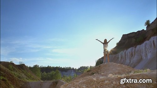 Strong happy woman tourist is reaching the point of her journey and standing with hands up in sunny