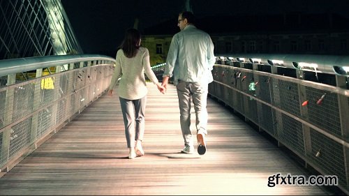 Couple walking holding hands on bridge in the night