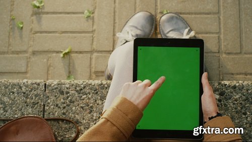 Girl is using tablet on lap outdoors at sunny day