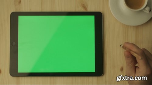 Tablet with green screen laying on a wooden table in landscape mode