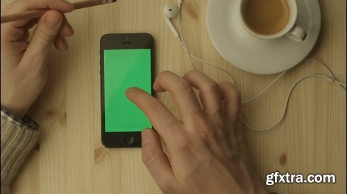 Phone with green screen laying on a wooden table