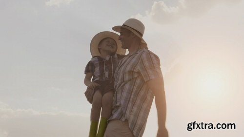 Proud farming father showing son the farm at sunset