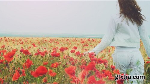 Young attractive woman dressed in white clothes is running-through a poppies field feeling happy and free slow motio filmed at 250-fps