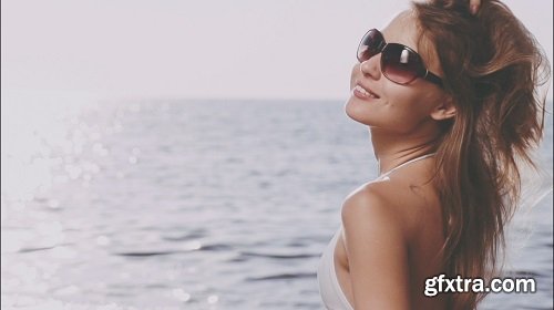 Beautiful young woman in bikini is styling her hair on the sea beach sunny summer by the sea