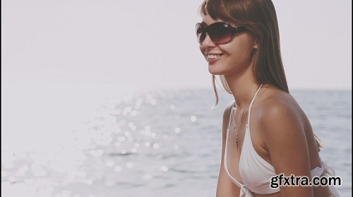 Beautiful young woman in bikini is styling her hair on the sea beach sunny summer by the sea