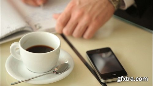 Cup of coffee on the table and the guy writing something