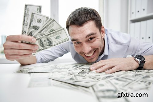 Happy businessman with heap of money in office