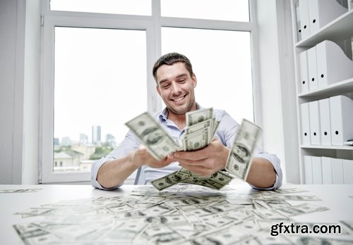 Happy businessman with heap of money in office