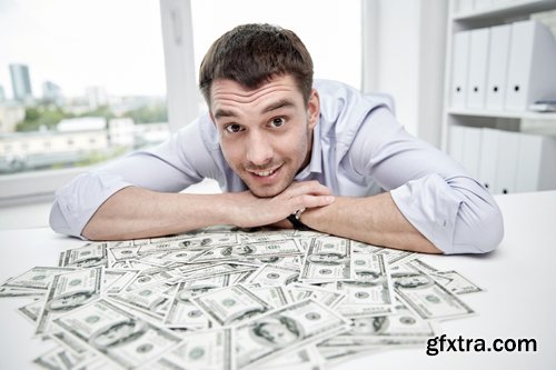 Happy businessman with heap of money in office