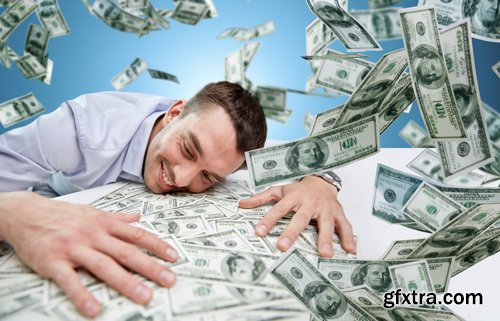 Happy businessman with heap of money in office