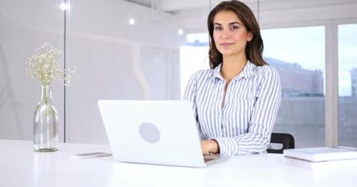 Smiling Young Hispanic Woman at Work looking Toward Camera - KXAGRDN