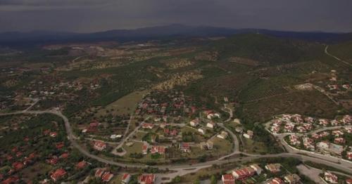 Flying Over Houses and Green Spaces in Trikorfo Beach, Greece - RJQ5BTN