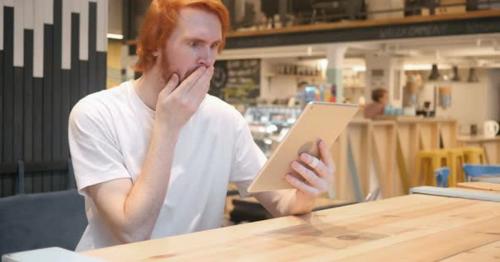 Shocked, Wondering Redhead Beard Man Using Tablet PC in Cafe - VMN2FX7