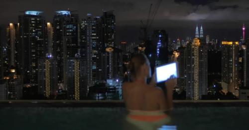 Woman Taking Notes In Tablet In The Swimming Pool On The Skyscraper Roof And Night City - MSNJWZ7