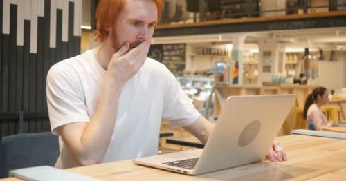 Astonished, Amazed Redhead Beard Man Working in Cafe - V82JKCX