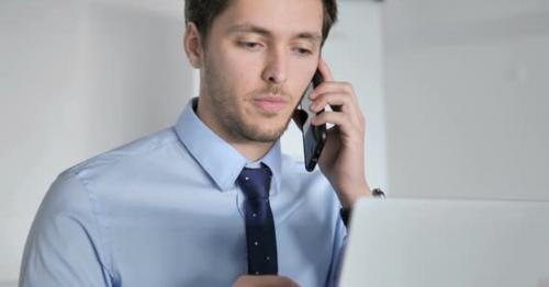 Close Up of Young Businessman Talking on Phone at Work - NJ968RH