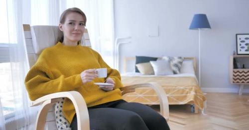 Relaxing Woman Drinking Coffee while Sitting on Casual Chair - VJGUTLN