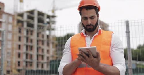 Architect Man Standing with Tablet on the Construction Site and Analyzing Scheme Project Plan - WCNTA37