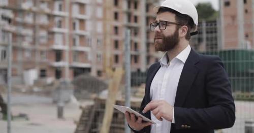 Architect Man Wearing Business Suit Standing with Tablet on the Construction Site and Analyzing - 4PDQVGF