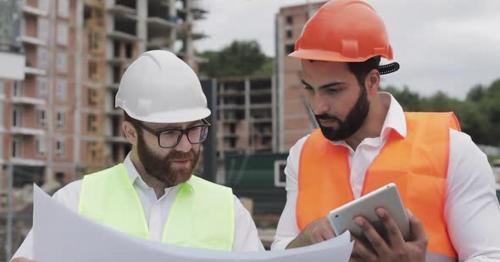 Building a Residential Complex or Business Center. Team of Engineers Men with a Tablet and Drawing - FDRT3CX