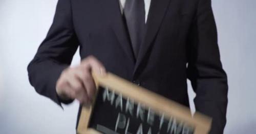 Marketing Plan Written on Blackboard Man in Black Suit Holding Sign Business - LYQKPGN