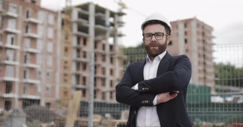 Portrait of Architect Man in Business Suit Standing on the Construction Site with Crossed Hands - GTY2M5F