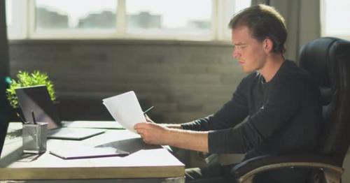 Young Thoughtful Businessman Sitting in the Office at the Table Near Notebook and Working - 7XSM2V9