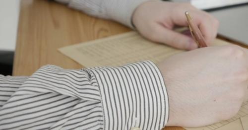 Businessman Sitting At Office Desk Signing a Contract - S76UYNQ