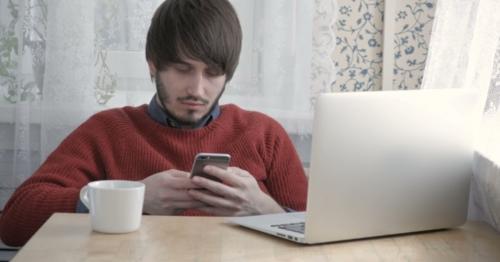 Happy Young Man Freelancer Working With Modern Laptop And Phone In Cafe Taking Cup Of Coffee - GQ49SZ3