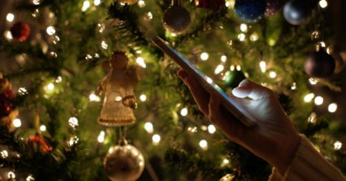 Using Smartphone At Christmas Tree Lights Background - EQXVACZ