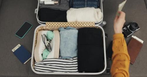 Woman's Hands Packing Suitcase for a Journey on the Bed at Home. Travel Preparations - BZU2QE6