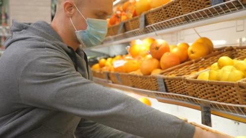 Videohive - Man with Medical Face Mask Selects Lemons in Store. Guy Choose Fruits in Supermarket. Purchase Food