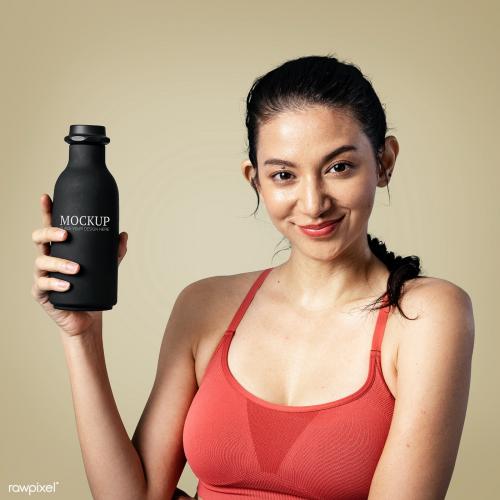 Sporty woman holding a black bottle mockup - 2253804