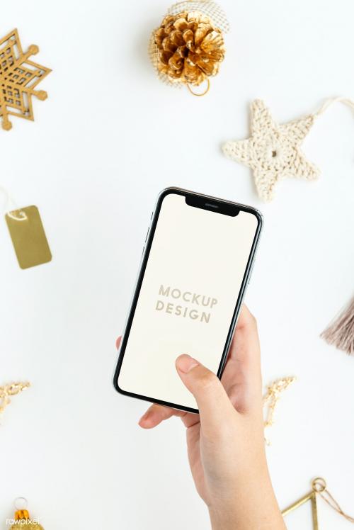 Woman holding her phone above gold Christmas ornaments mockup - 1231713