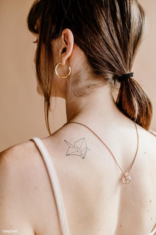 Woman with a paper bird tattoo on her shoulder - 1235467