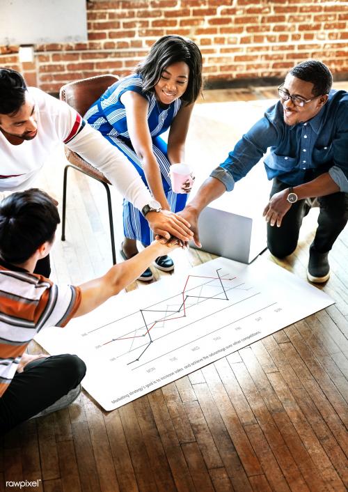 Diverse team stacking hands over a project plan mockup - 2051830