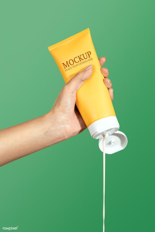 Woman squeezing cream from a yellow tube psd mockup - 2056062