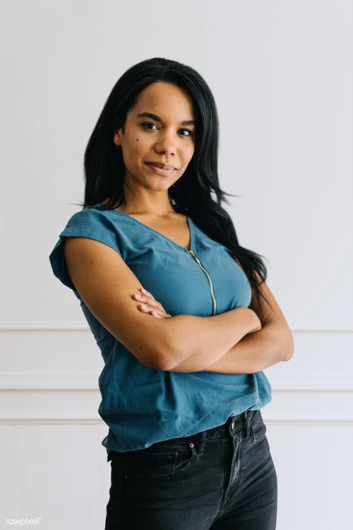 Happy empowering black woman standing by a white wall - 1220742