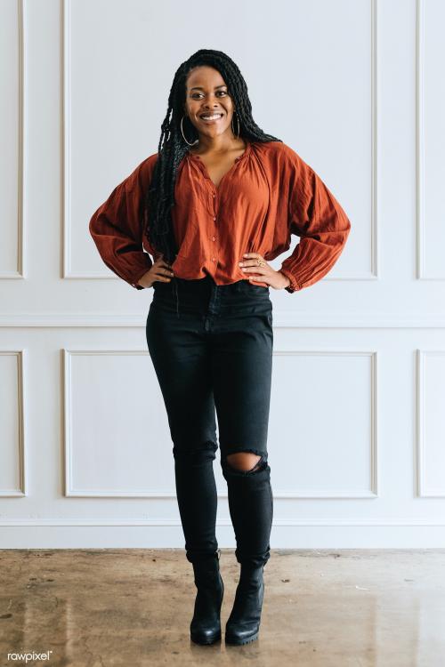 Happy empowering black woman standing by a white wall - 1220754