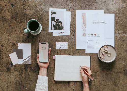 Woman holding a mobile phone mockup while writing on a notebook - 1224173