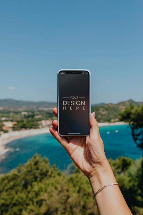 Woman holding a phone at the beach mockup - 1228449